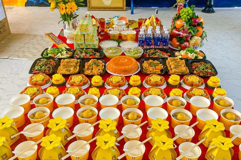 Mâm cúng chay với xôi, chè, các món chay, trái cây và hoa bày trên bàn phủ khăn đỏ