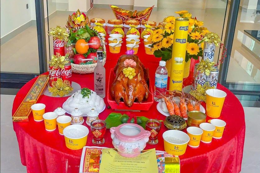 Mâm lễ với heo quay nguyên con, giỏ trái cây, hoa đồng tiền vàng và nhang đèn trên bàn tròn phủ khăn đỏ