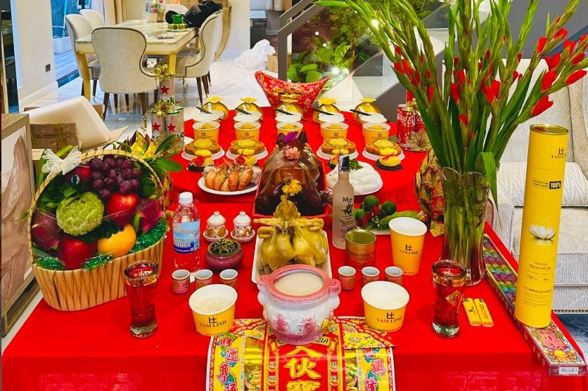 Mâm cúng gồm heo quay, gà luộc, giỏ trái cây, hoa lay ơn và rượu bày trên bàn phủ khăn đỏ