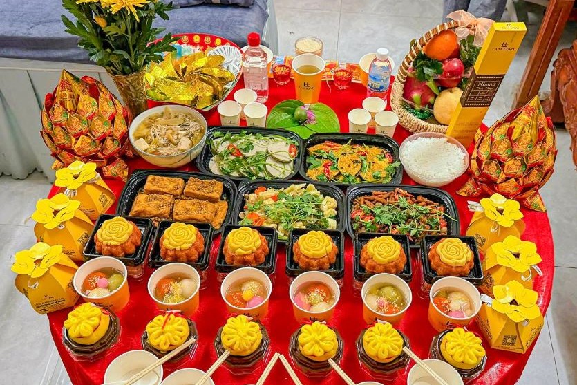 Mâm cúng gồm trái cây, xôi, chè, mâm cơm chay và hoa cúc vàng bày trên bàn tròn phủ khăn đỏ
