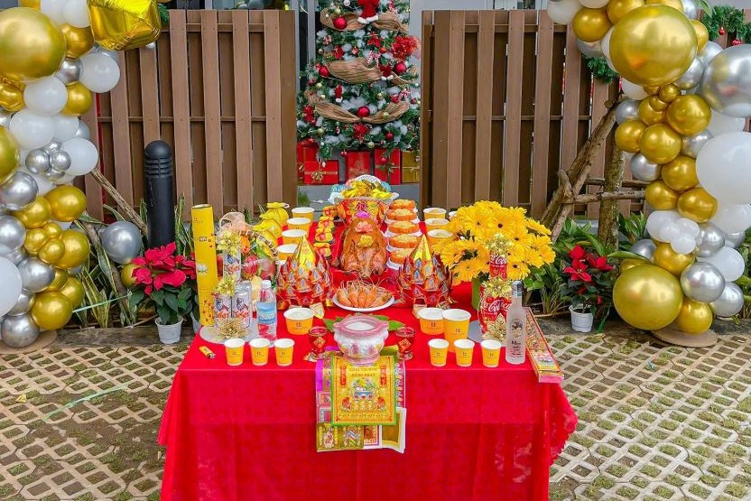 Mâm cúng khai trương với heo quay, bộ tam sên, hoa đồng tiền và trái cây bày trên bàn phủ khăn đỏ