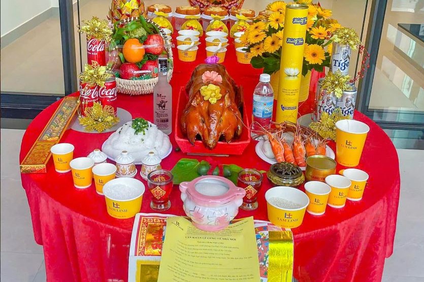 Mâm cúng giỗ tổ nghề xây dựng với heo quay, tôm, trái cây, hoa và nhang đèn trên bàn tròn phủ khăn đỏ