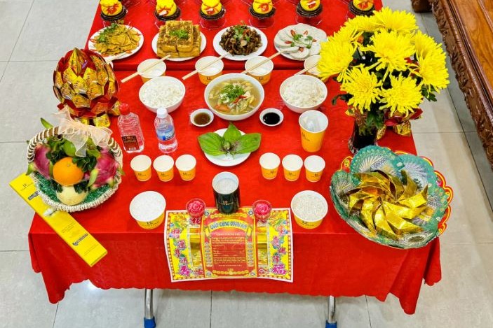 Mâm lễ chay với xôi, chè, cơm canh chay, trái cây và hoa cúc vàng bày trên bàn phủ khăn đỏ